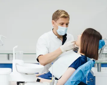 close-up-portrait-beautiful-young-lady-sitting-dental-chair-while-stomatologist-hands-sterile-gloves-holding-tooth-samples 1 (1)